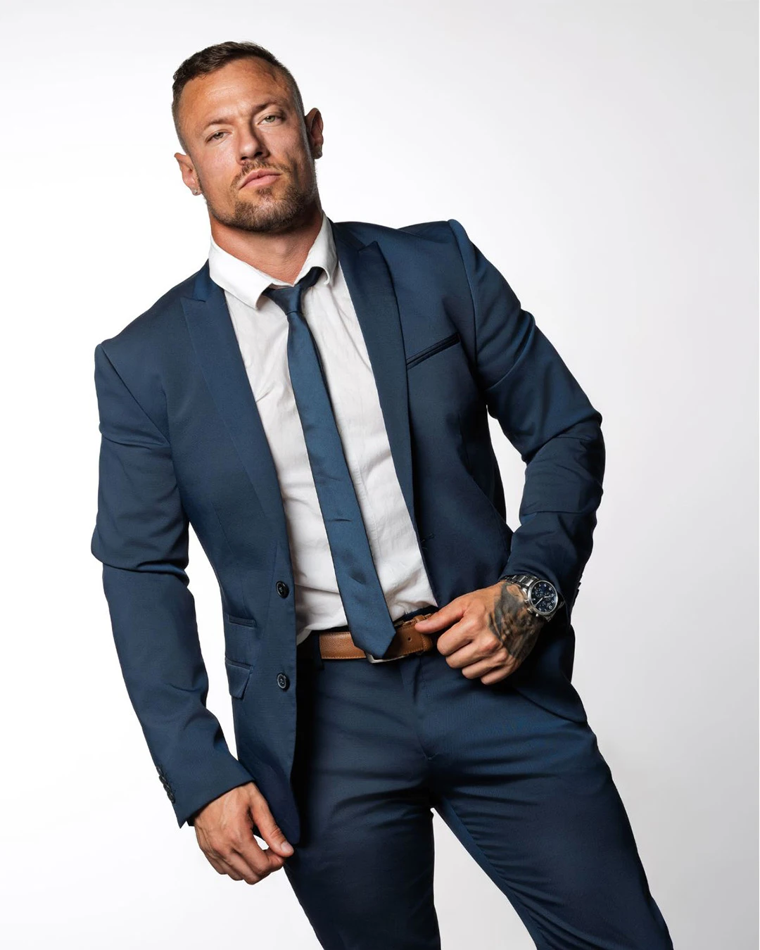 Drogo, artiste des Golden Boys, posant en costume bleu élégant