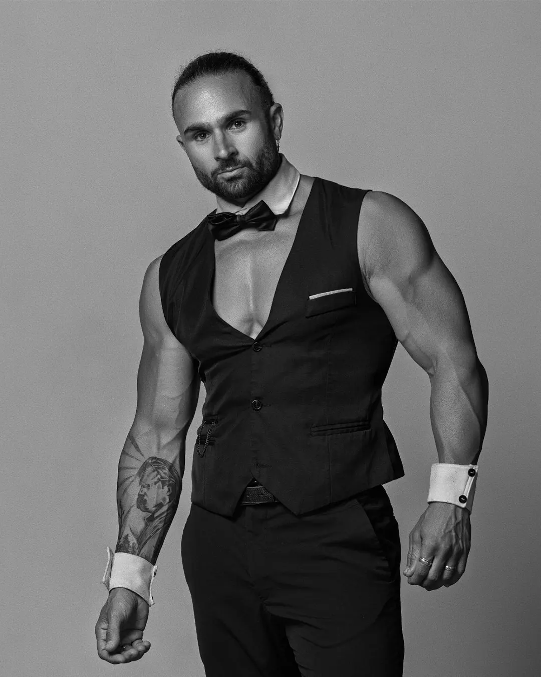 Enzo, artiste des Golden Boys, posant en costume noir avec nœud papillon style chic