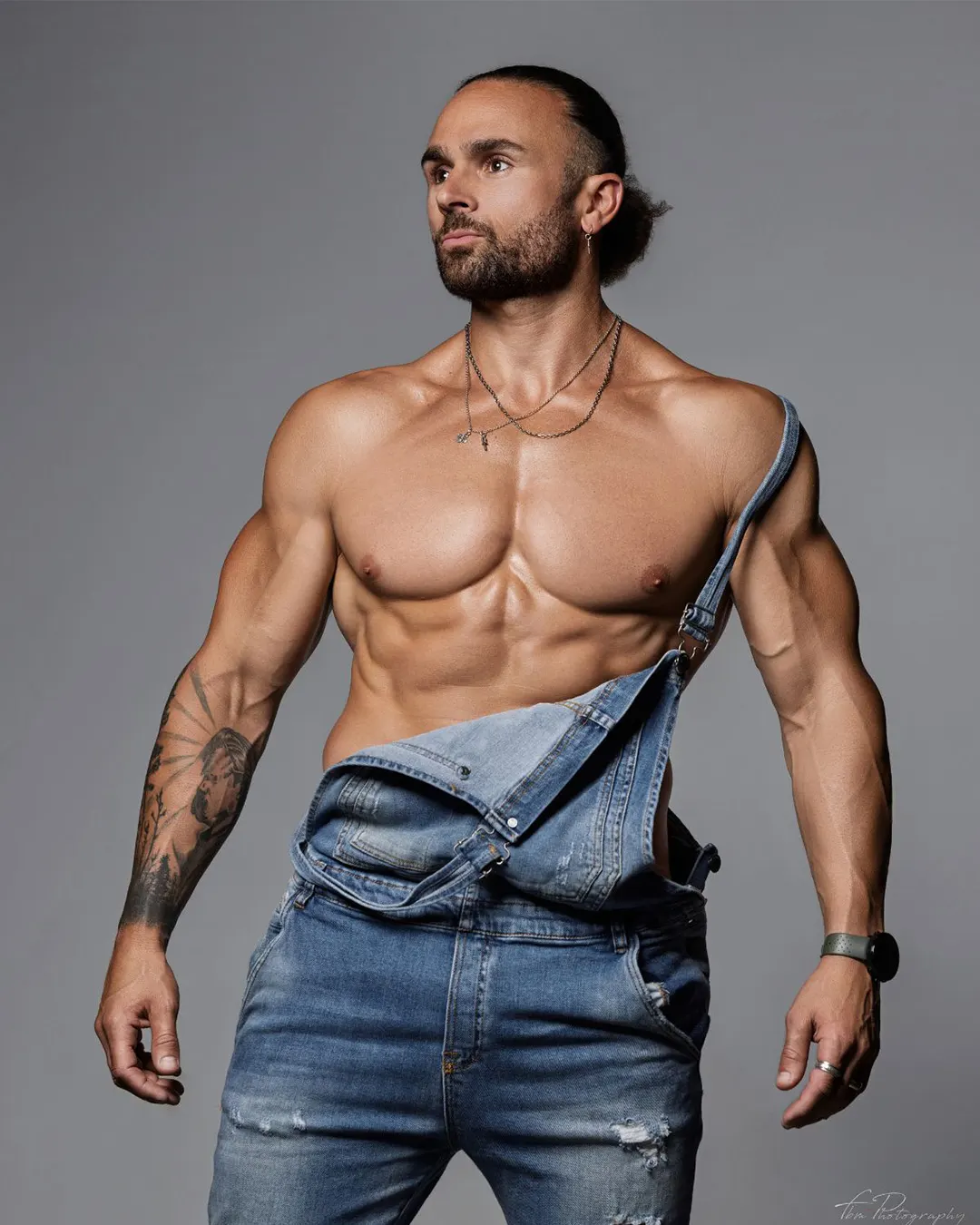 Enzo, artiste des Golden Boys, posant torse nu en salopette jean