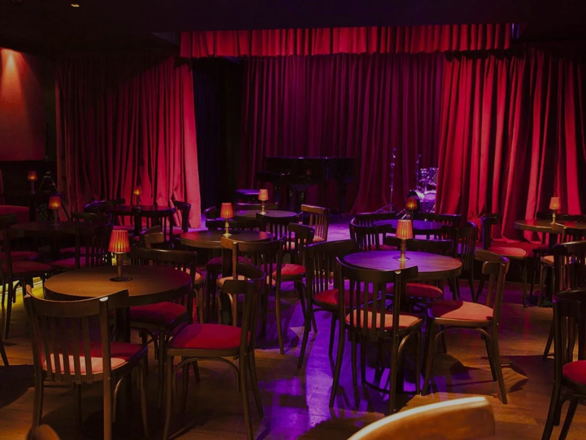 Salle de dîner-spectacle avec scène et rideaux rouges pour une prestation Golden Boys Show