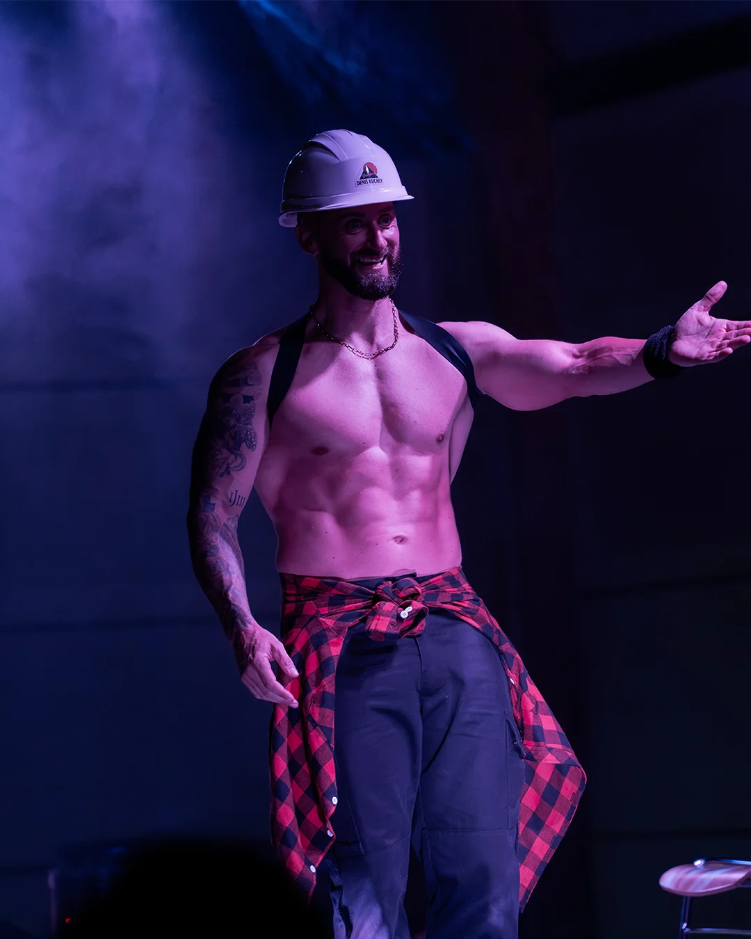 Karl en tenue de chantier invitant une participante à monter sur scène