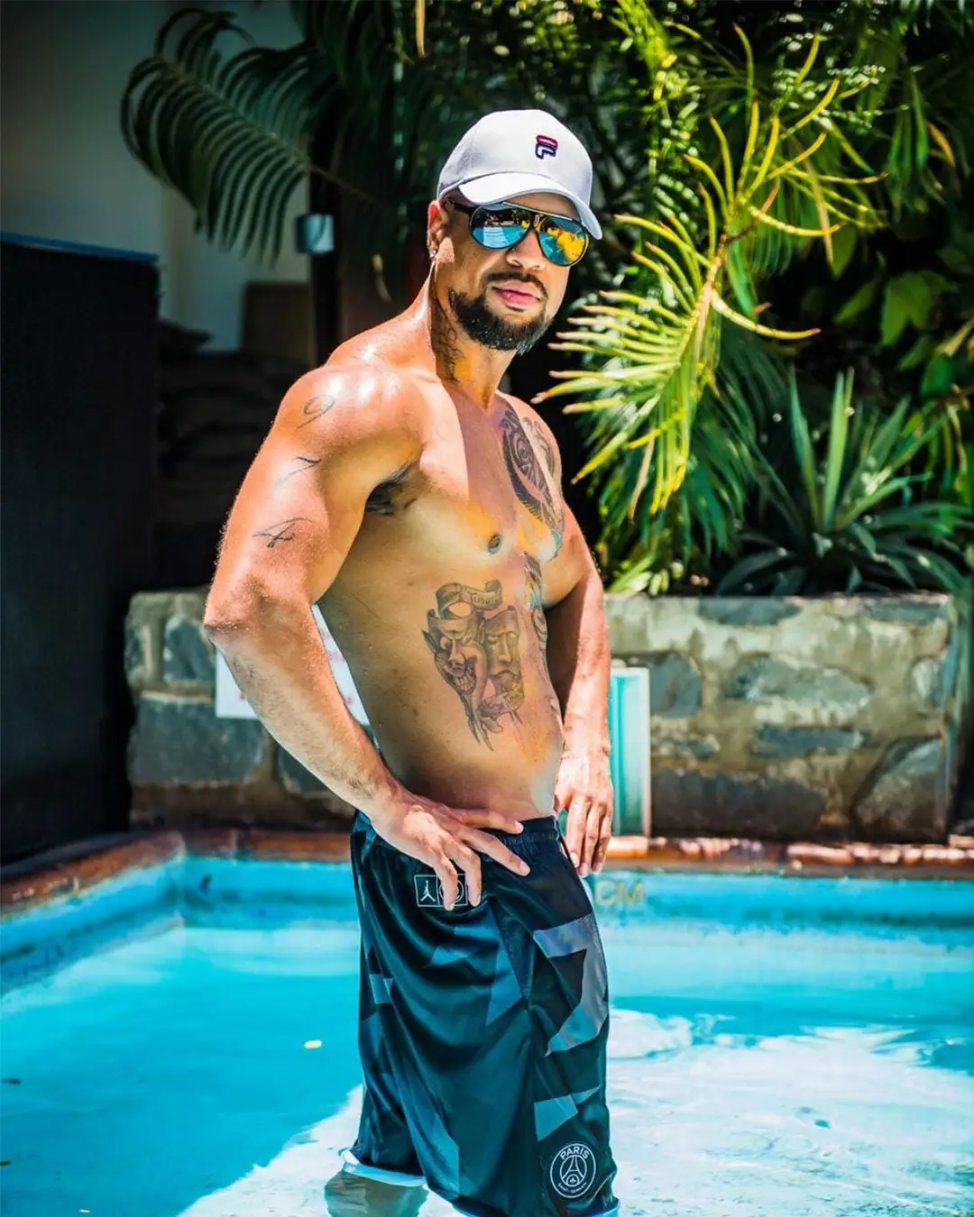Ross, chorégraphe de la troupe Golden Boys, torse nu, casquette let es pieds dans une piscine