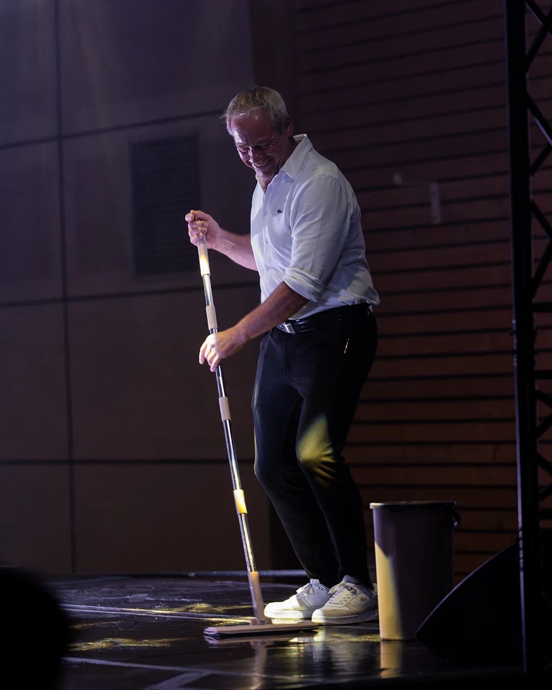 Thierry, président des Amis du Spectacle Vivant, souriant sur scène avec une serpillière
