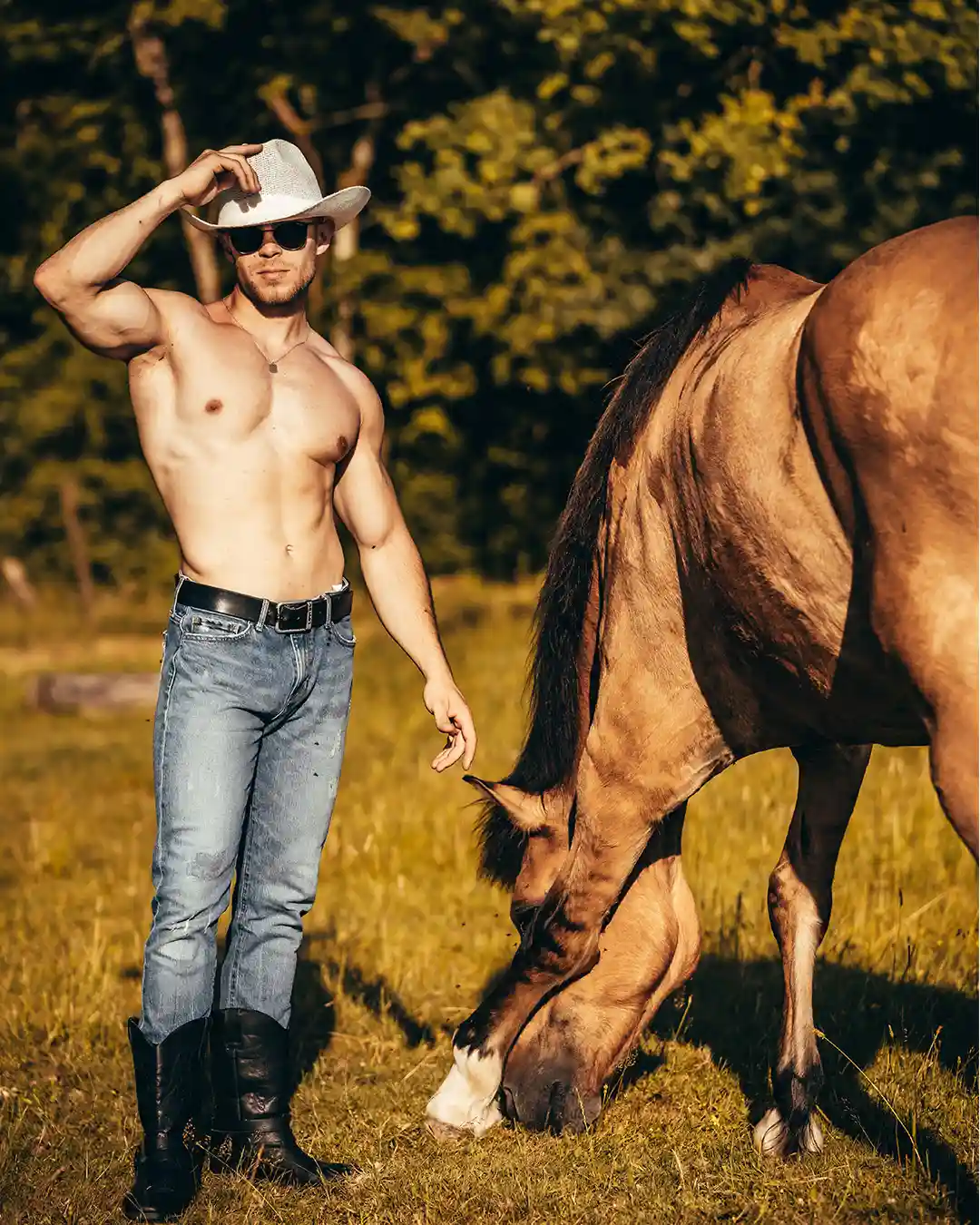 Travis, artiste des Golden Boys, torse nu près d'un cheval avec une allure de cowbow